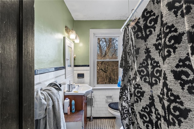 bathroom featuring vanity, a wainscoted wall, tile walls, toilet, and tile patterned floors