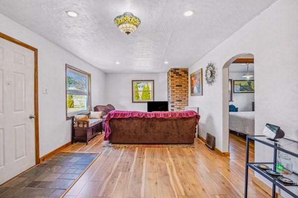 living room featuring recessed lighting, baseboards, wood-type flooring, and arched walkways