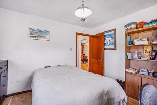 bedroom featuring arched walkways and light wood-style flooring