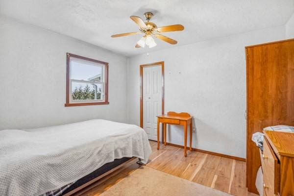 bedroom with a ceiling fan, light wood-style floors, and baseboards