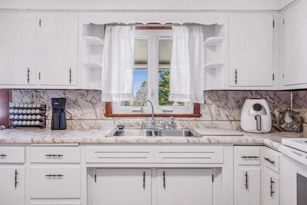 kitchen with a sink, white cabinets, light countertops, and open shelves