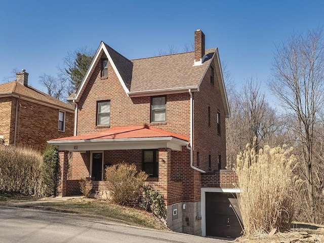 view of front of house featuring a porch, roof with shingles, an attached garage, brick siding, and a chimney