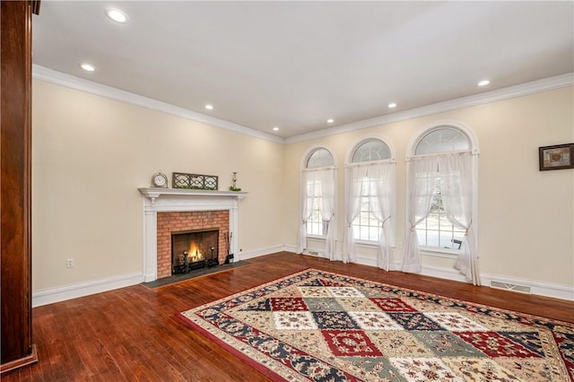 living area featuring visible vents, ornamental molding, wood finished floors, baseboards, and a brick fireplace