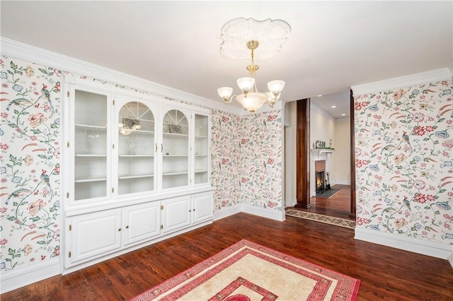 unfurnished room featuring a notable chandelier, dark wood finished floors, and wallpapered walls