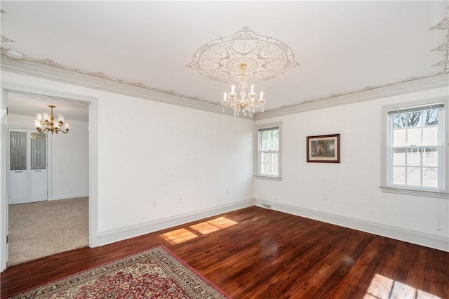 spare room featuring a chandelier, crown molding, baseboards, and wood finished floors