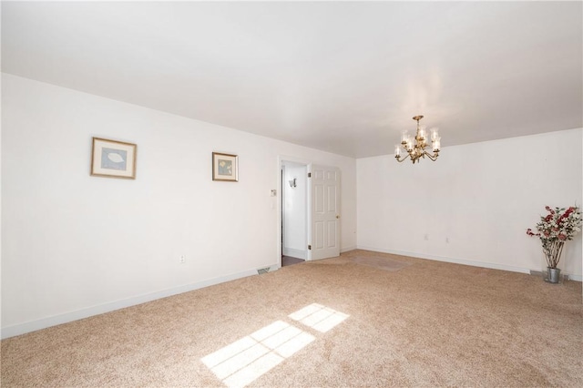 spare room featuring light colored carpet, baseboards, and a chandelier