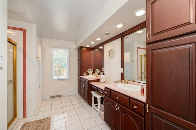 bathroom featuring tile patterned floors, a stall shower, two vanities, and a sink