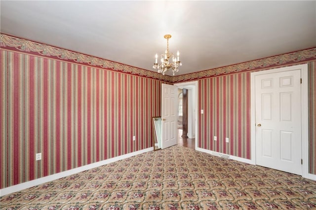 carpeted spare room with wallpapered walls, baseboards, and a chandelier