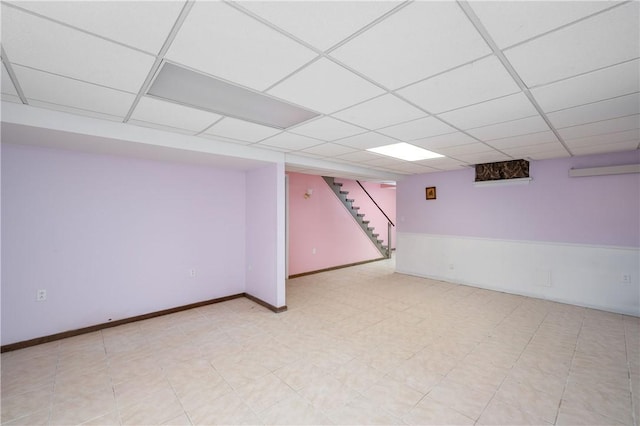 finished basement with stairway, a paneled ceiling, and baseboards