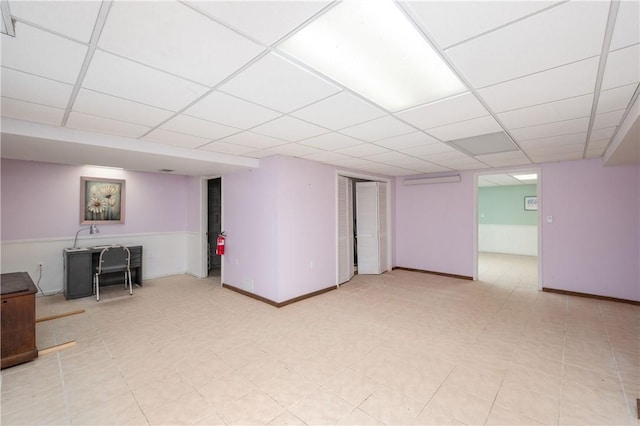 finished basement with baseboards and a paneled ceiling