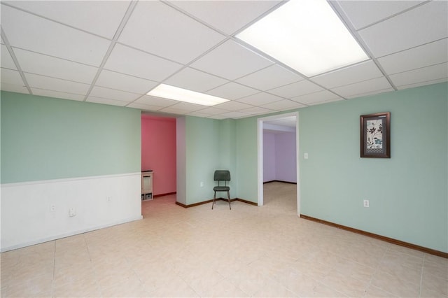 spare room featuring a drop ceiling and baseboards