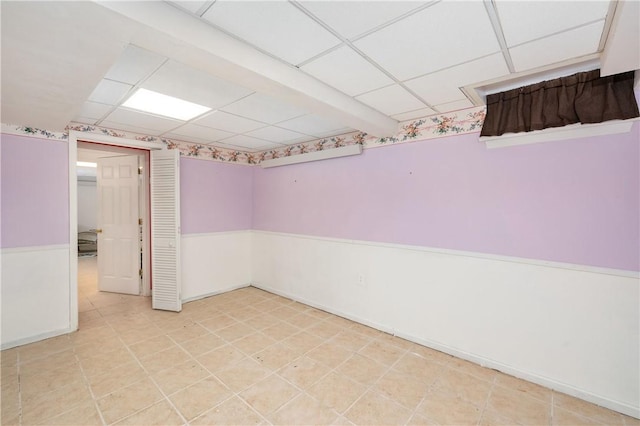 unfurnished room featuring a wainscoted wall and a paneled ceiling