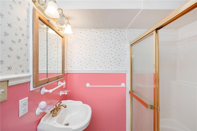 full bathroom featuring wallpapered walls, a shower stall, and a sink