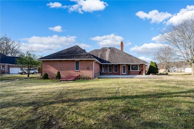 back of property featuring a yard, brick siding, and a chimney