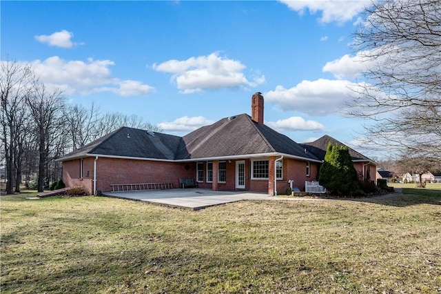 rear view of property with a yard, a patio, brick siding, and a chimney