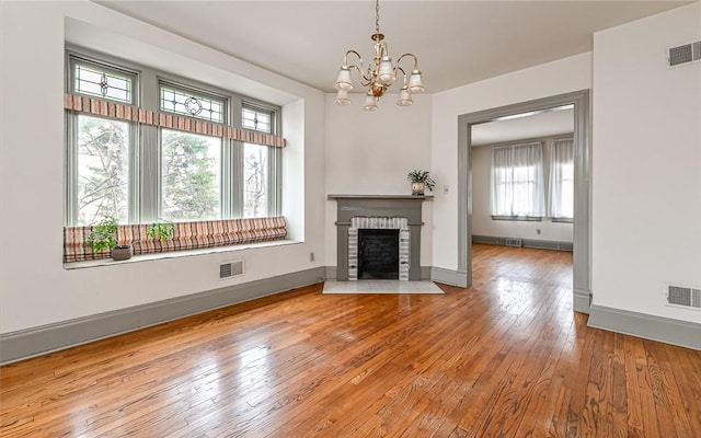 unfurnished living room with a chandelier, visible vents, and wood-type flooring