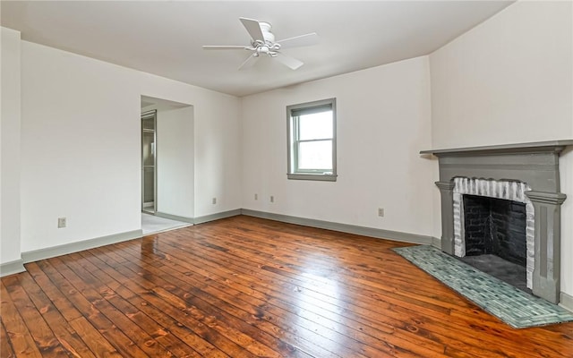 unfurnished living room featuring a fireplace with flush hearth, wood-type flooring, baseboards, and a ceiling fan