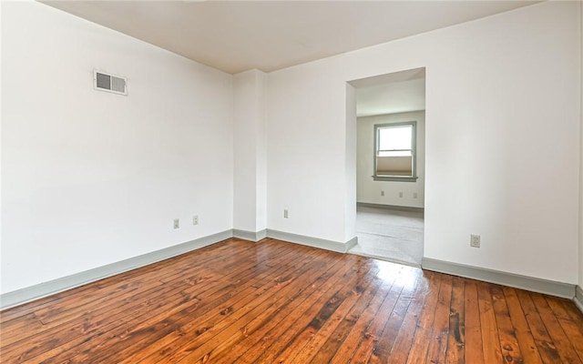 unfurnished room with baseboards, visible vents, and wood-type flooring