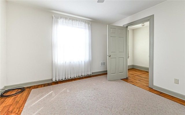 unfurnished room with visible vents, wood finished floors, and baseboards