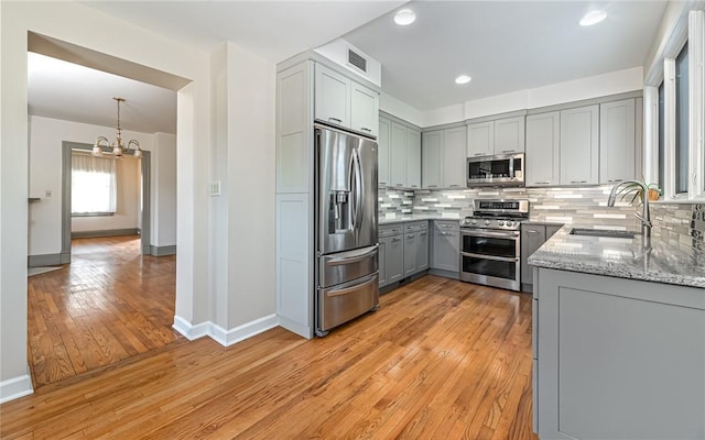 kitchen with visible vents, gray cabinetry, decorative backsplash, stainless steel appliances, and a sink