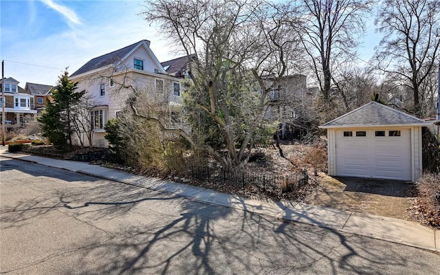 view of front of property featuring a garage, an outdoor structure, driveway, and a shingled roof