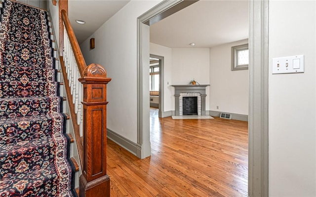 stairway featuring visible vents, a fireplace, baseboards, and wood finished floors