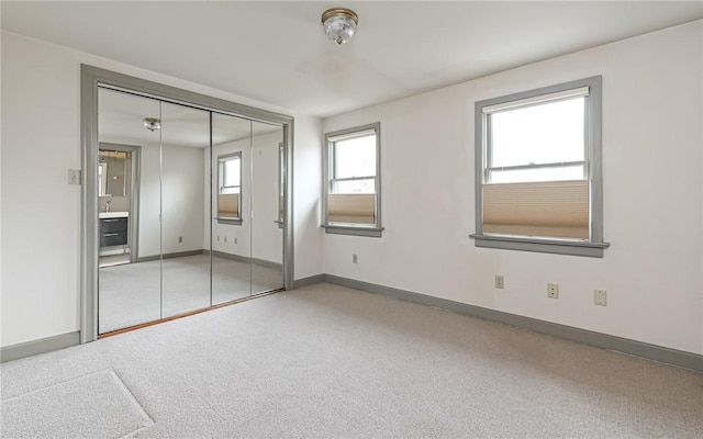 unfurnished bedroom with a closet, baseboards, and carpet flooring