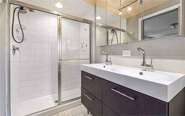 bathroom featuring a sink, double vanity, a shower stall, and tile patterned floors