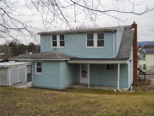 rear view of property featuring a patio area, a lawn, and a chimney