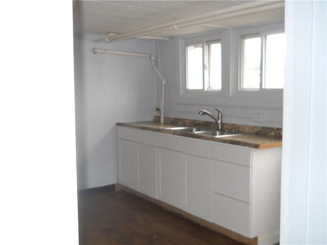 kitchen with dark wood finished floors, white cabinetry, and a sink