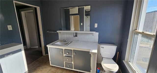 bathroom with decorative backsplash, toilet, and vanity