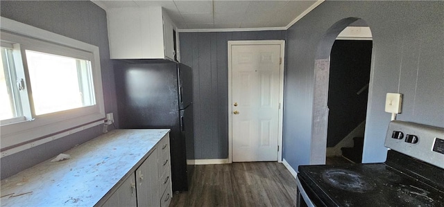 kitchen with dark wood-type flooring, freestanding refrigerator, arched walkways, crown molding, and stainless steel electric range oven