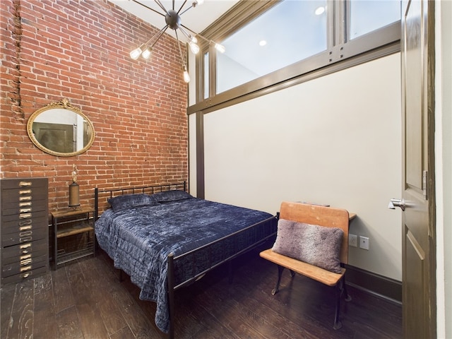 5267 Holmes St Unit 205, Lawrenceville, PA 15201 - bedroom with a notable chandelier, hardwood / wood-style floors, brick wall, baseboards, and a towering ceiling