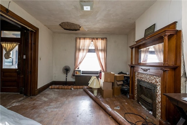 living area featuring a fireplace, radiator heating unit, baseboards, and wood finished floors
