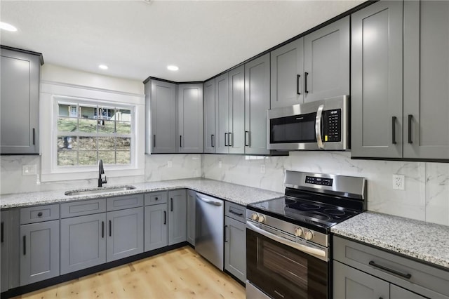 kitchen featuring stainless steel appliances, gray cabinets, and a sink