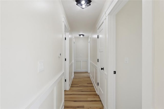hallway with light wood-type flooring and a decorative wall