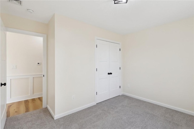 unfurnished bedroom featuring visible vents, a closet, baseboards, and carpet floors