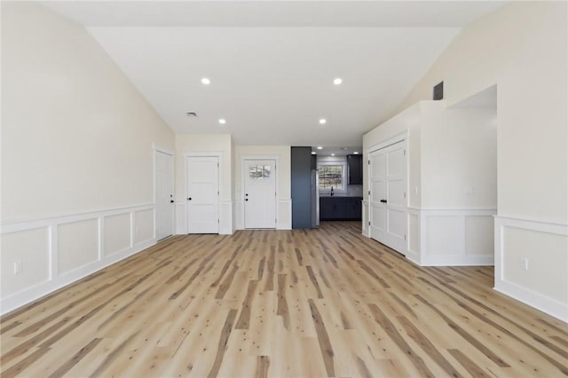 unfurnished living room with recessed lighting, a wainscoted wall, light wood-style floors, and a decorative wall