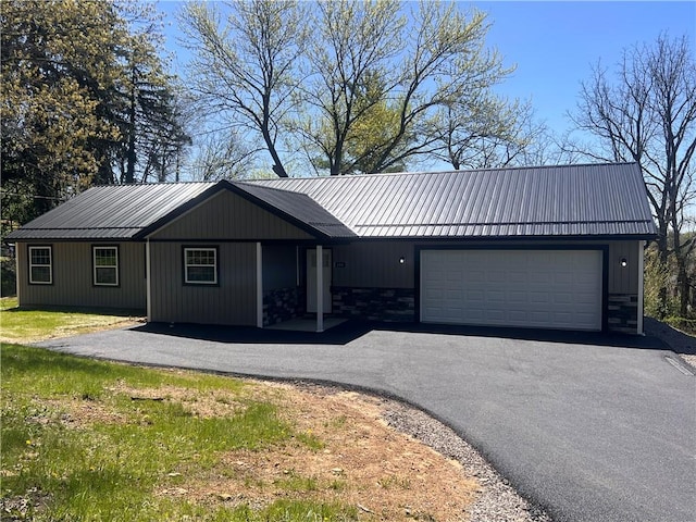 single story home with driveway, metal roof, and a garage