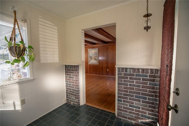unfurnished room with ornamental molding, healthy amount of natural light, dark tile patterned flooring, and a decorative wall