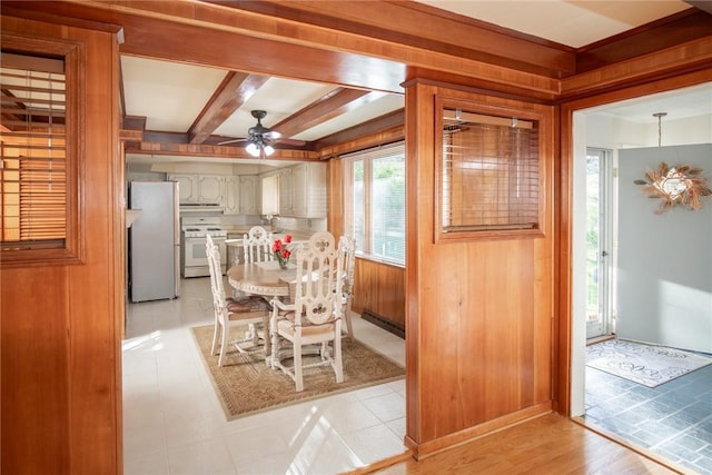 dining room with ceiling fan, wooden walls, and beam ceiling