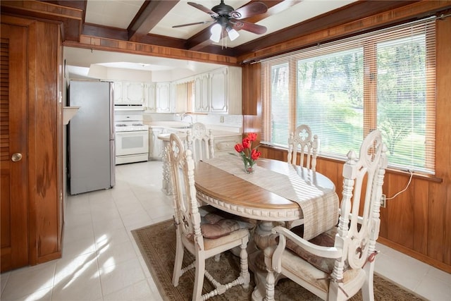 dining room featuring plenty of natural light, a ceiling fan, wood walls, and light tile patterned flooring
