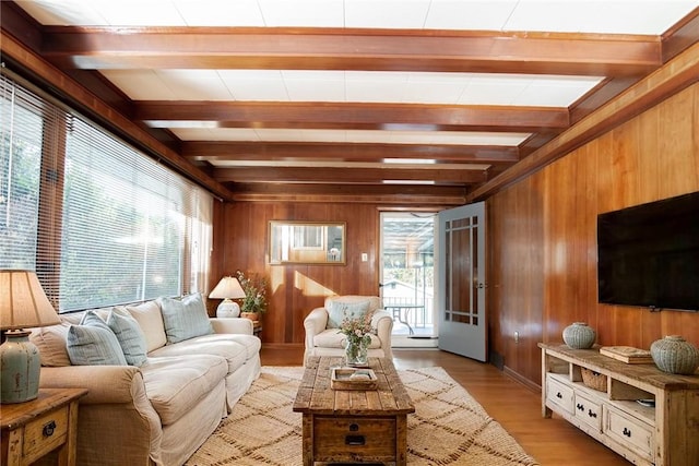 living room with beamed ceiling, wood walls, and light wood-style flooring