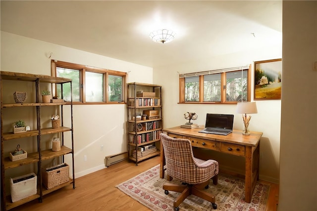 office space with baseboard heating, light wood-style floors, and baseboards