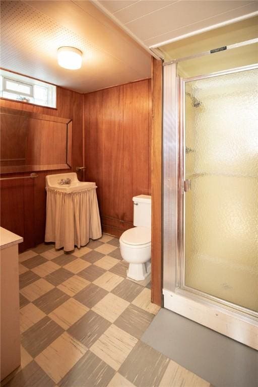 full bath featuring tile patterned floors, a stall shower, wooden walls, and toilet