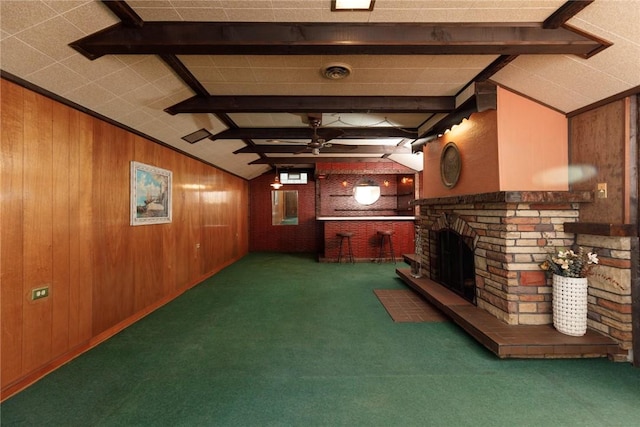 unfurnished living room with wooden walls, a fireplace, a ceiling fan, and carpet floors
