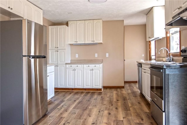 478 Spang Ave, Leechburg Boro, PA 15656 - kitchen with light wood finished floors, a sink, white cabinets, appliances with stainless steel finishes, and a textured ceiling
