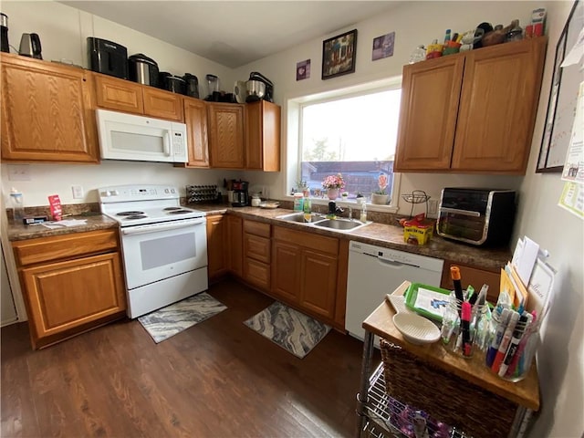 kitchen featuring dark wood-style flooring, white appliances, dark countertops, a sink, and brown cabinetry