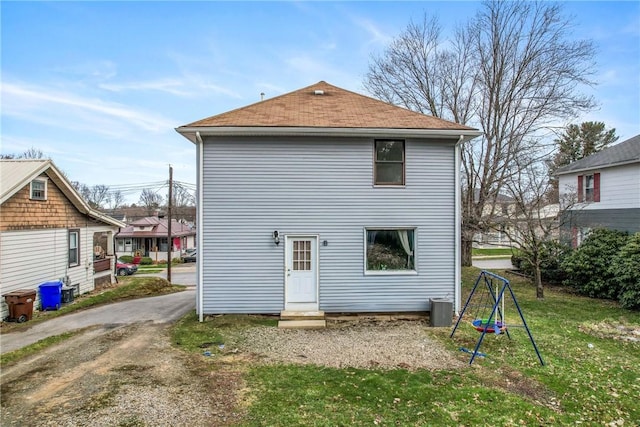 back of property with central air condition unit and a yard