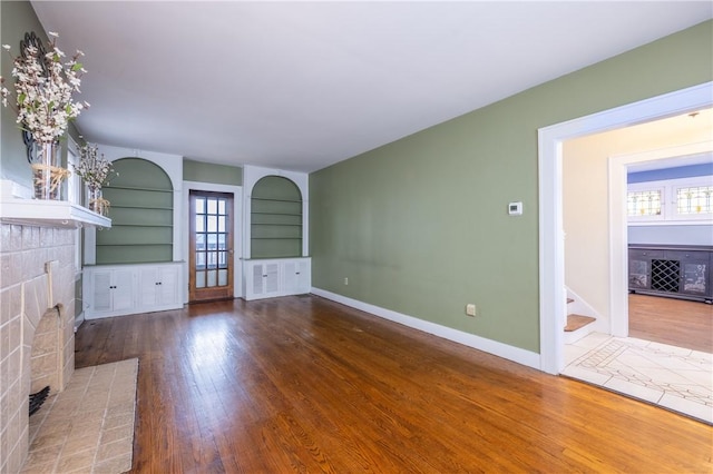 3361 Portola Ave, Observatory Hill, PA 15214 - unfurnished living room with a brick fireplace, hardwood / wood-style flooring, stairway, and healthy amount of natural light